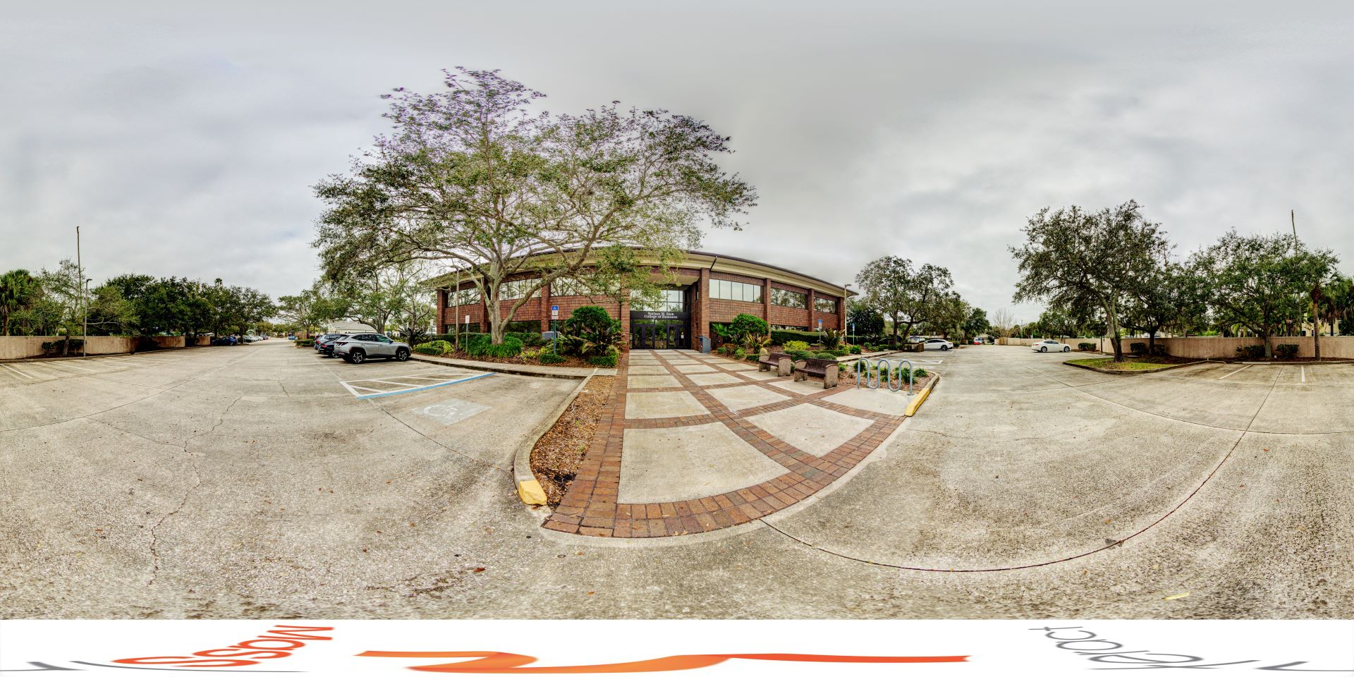 Bisk College building entrance with parking lot and trees